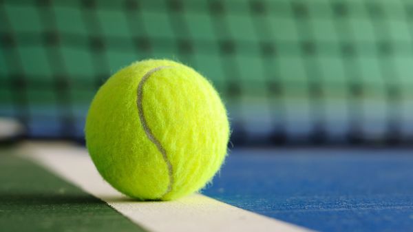 Tennis ball on the court line with net in the background